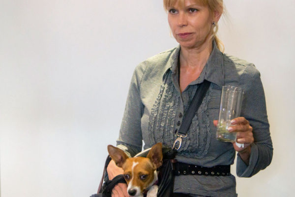 woman holding glass with dog in a purse
